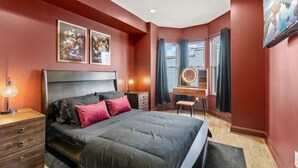 Une chambre à coucher comprenant un lit, un bureau, une chaise, une commode et un miroir.