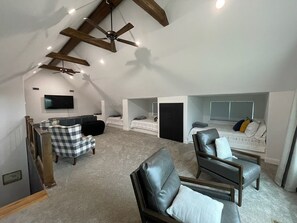 Ein Schlafzimmer im Loft-Stil mit geneigter Decke, integrierten Sitzmöglichkeiten, einem Flachbildfernseher und einem Bett mit Kopfteil.