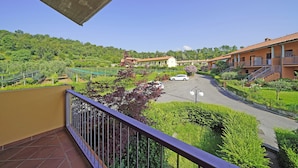 Ein Hotel mit einer Terrasse mit Blick auf einen Parkplatz und üppiges Grün.