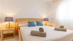 Ein ordentlich bezogenes Bett mit zwei Handtüchern, einem hölzernen Kopfteil und zwei Nachttischlampen.