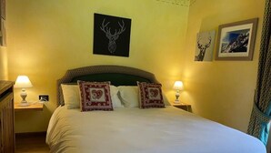 A neatly made bed with white linens and two decorative pillows, a wall-mounted deer head artwork, and two framed pictures on the wall. - Espoire cir 0025 (La Salle)
