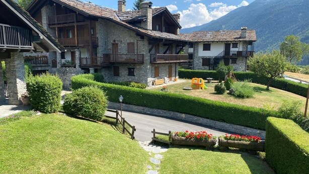A traditional stone building with multiple balconies and a well-maintained garden with a pathway leading to the entrance. - Espoire cir 0025 (La Salle)