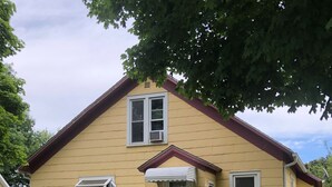 A two-story house with a front porch, a small garden, and a pathway leading to the entrance.