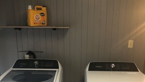 A laundry area with two Whirlpool washers and a shelf above holding a yellow detergent bottle.