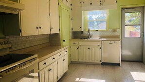 A kitchen with white cabinets, a built-in oven, and a window above the sink.