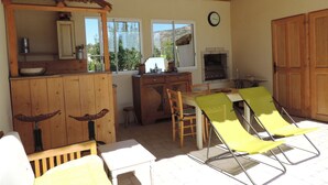 A rustic kitchen with wooden cabinets, a built-in grill, and a dining area with yellow chairs. - Bed and breakfast, private parking, SWIMMING POOL (Cavaillon)