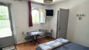 A bedroom with a bed, a desk, a chair, a TV, and a door. - Bed and breakfast, private parking, SWIMMING POOL (Cavaillon)