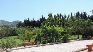 A gravel court with a wooden fence, red benches, and green trees in the background. - Bed and breakfast, private parking, SWIMMING POOL (Cavaillon)