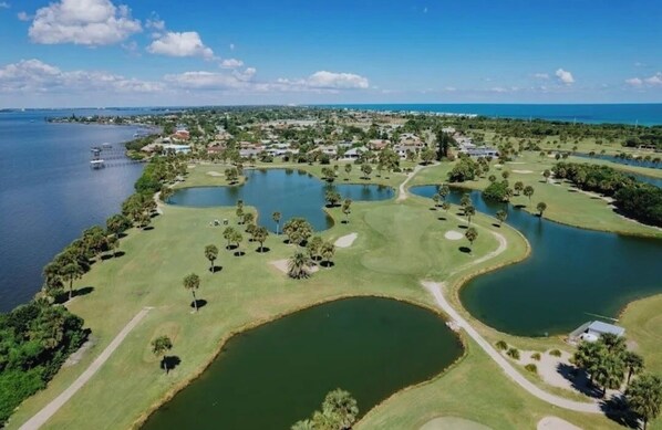 Ein Golfplatz mit mehreren Teichen und Blick auf den Ozean.