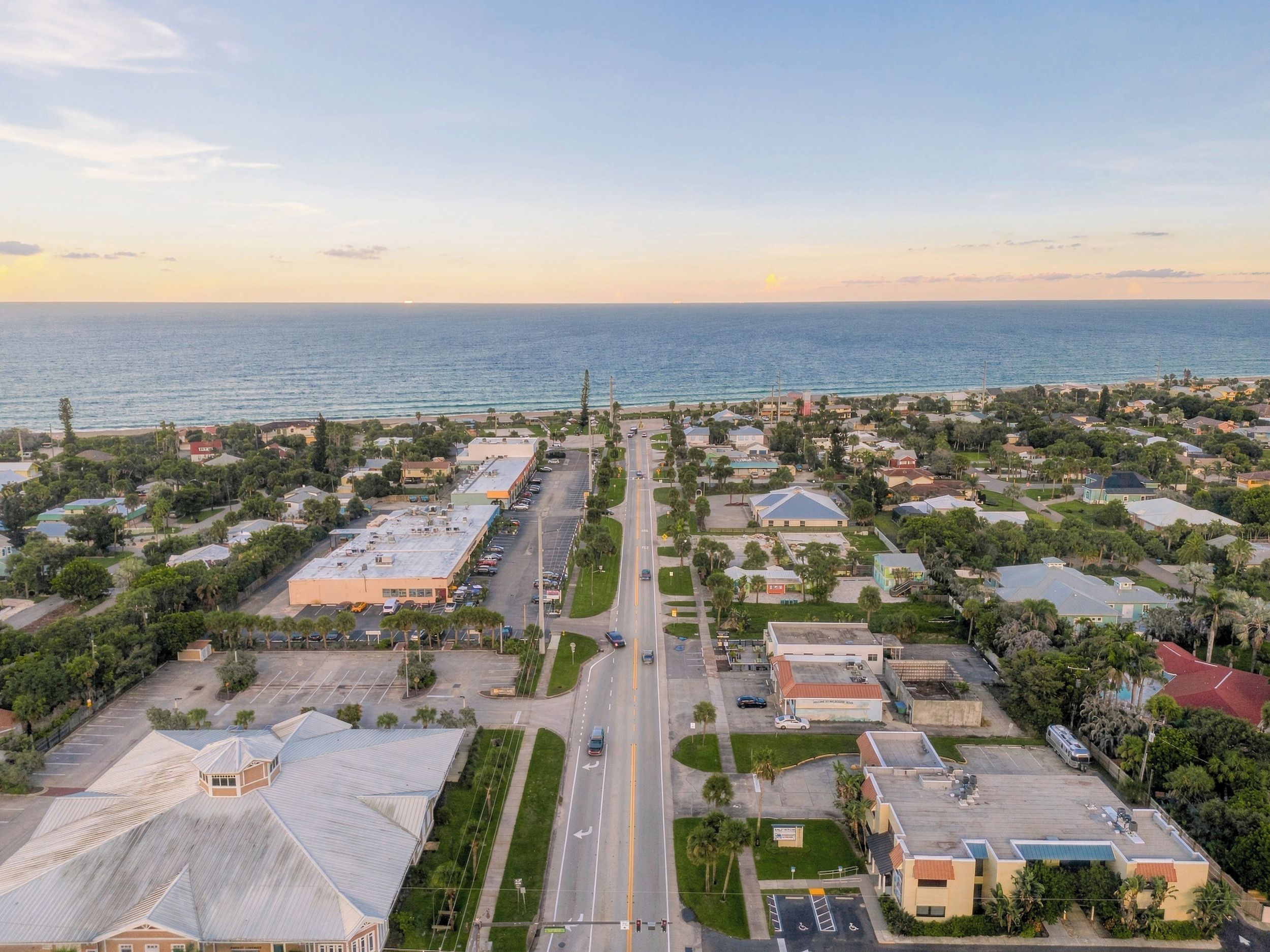 An aerial view of a coastal residential area with streets, houses, and a beach.