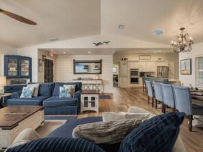 A spacious living room with a blue sofa, a wooden coffee table, and a dining area with patterned chairs.