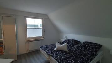 Une petite chambre à coucher, bien rangée, avec un lit, une chaise et une fenêtre.