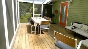 Une terrasse couverte avec une table et des chaises, un banc et un canapé.