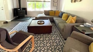 Un salon comprenant un canapé, une table basse, un tapis à motifs, un ventilateur de plafond et une cheminée.