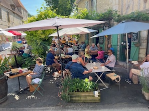 An outdoor café with tables and umbrellas, surrounded by greenery and stone buildings. - Newly renovated three storey Townhouse with garden, pool and lovely sun terrace. (Bergerac)