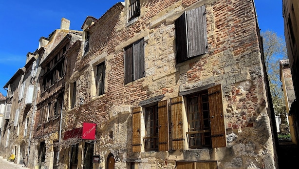 Ein historisches Steinhaus mit Holzhörnern, Bogenportalen und einer gepflasterten Straße.