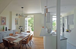 A modern kitchen with a central island, a dining area with a long table and chairs, and a large window providing natural light. - Newly renovated three storey Townhouse with garden, pool and lovely sun terrace. (Bergerac)