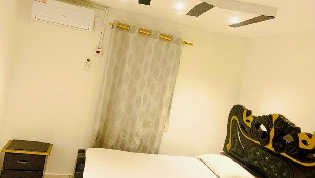 A bedroom with a bed, a nightstand, an air conditioning unit, and a curtain. - Mountains View Villa  (Freetown)