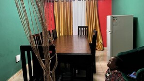 A dining area with a table, chairs, a hanging decorative item, and a refrigerator. - Mountains View Villa  (Freetown)