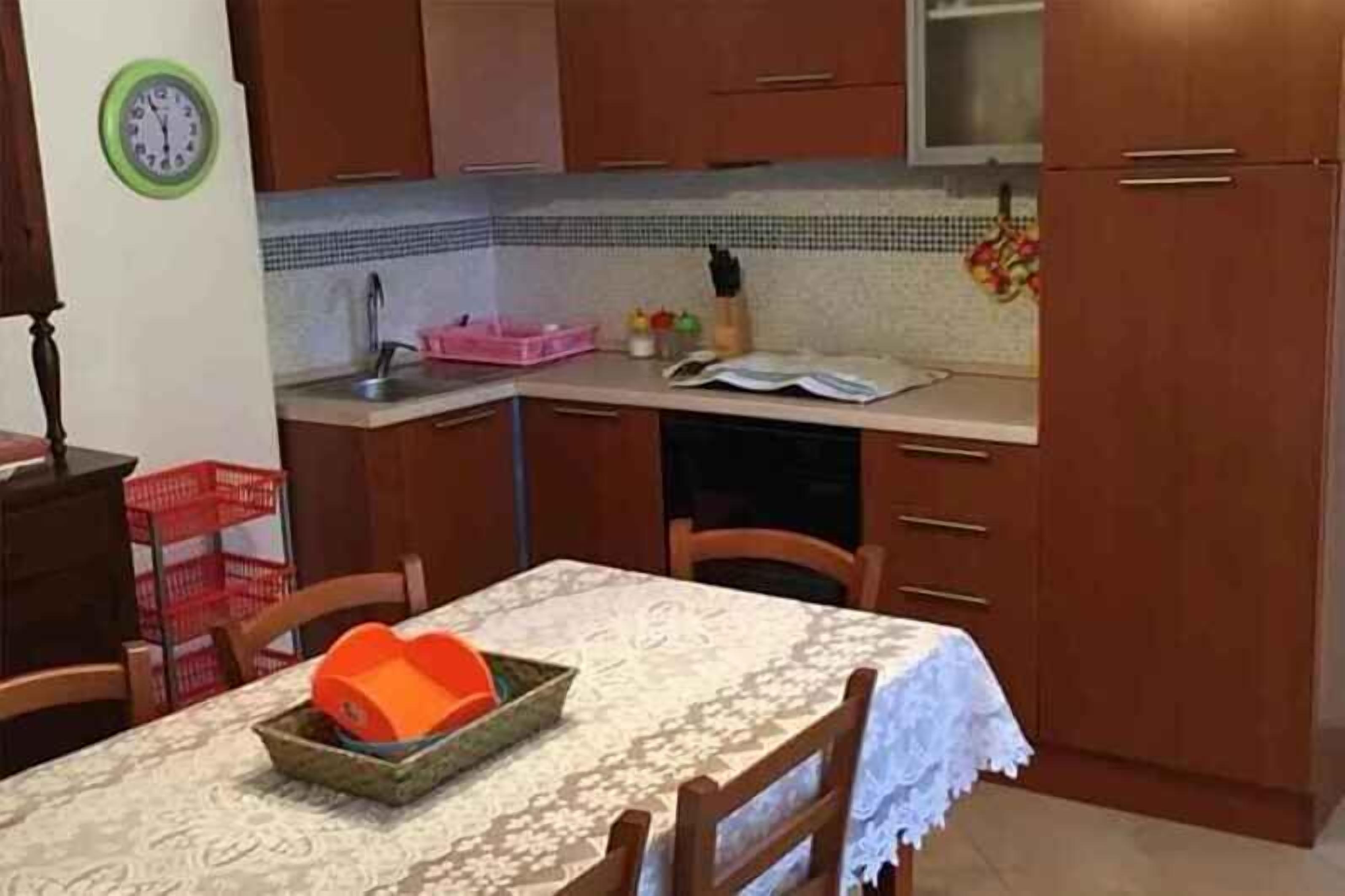 Una cocina con armarios de madera, un fregadero y una mesa de comedor con sillas.