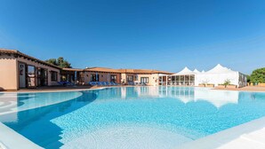 A swimming pool with lounge chairs and a covered area, surrounded by buildings with a consistent architectural style.