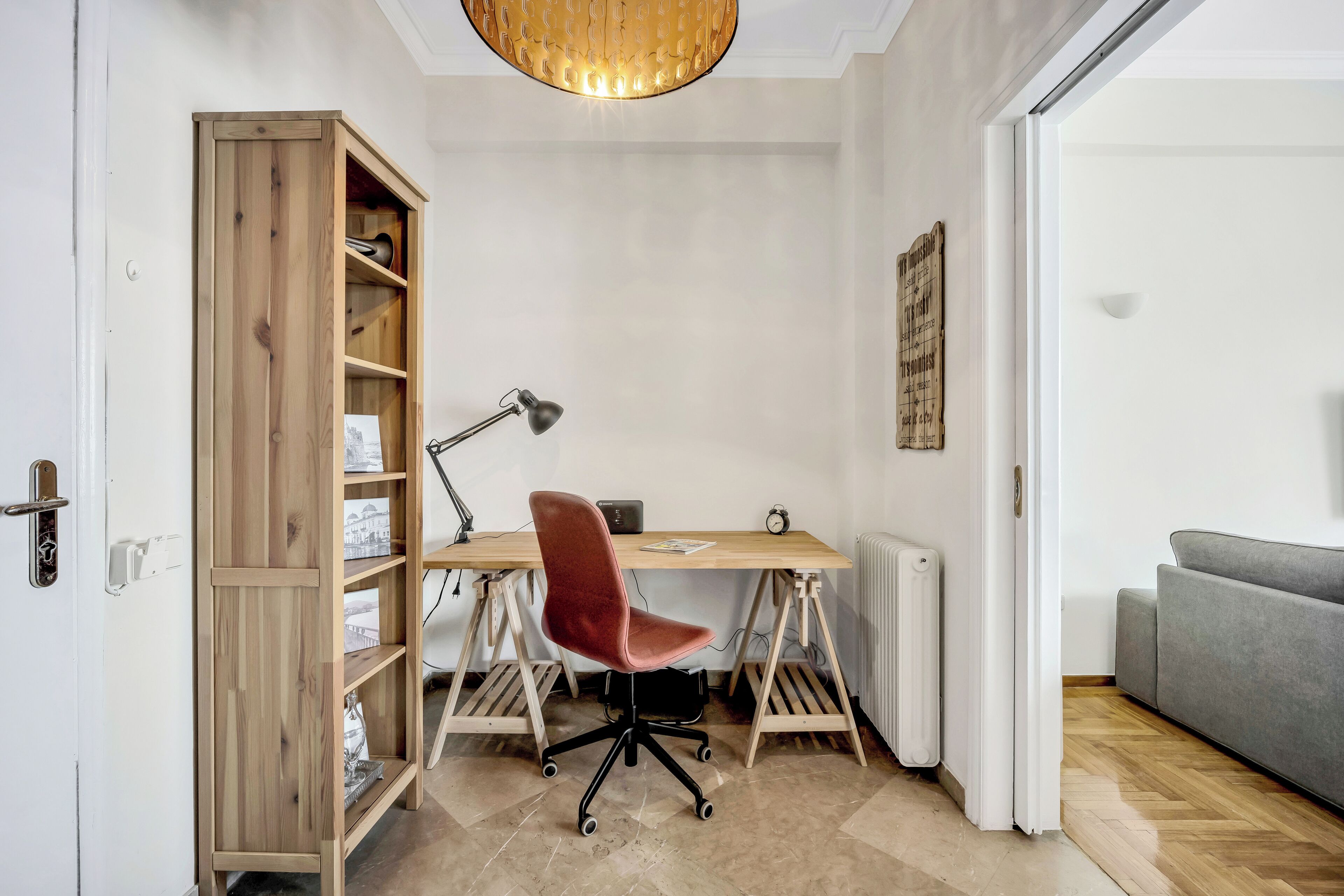 Un espace de travail avec un bureau en bois, une chaise rouge et une bibliothèque.