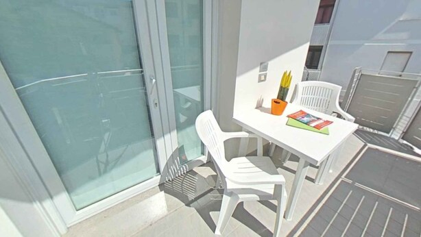 En balkon med et hvidt bord, stole og et magasin.
