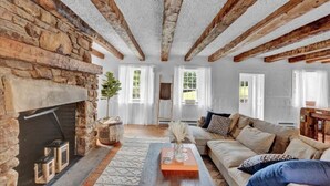 Un salon chaleureux avec des poutres apparentes, une cheminée en pierre et un canapé confortable.