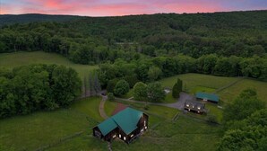 Vue aérienne d’une propriété rurale comprenant une grange, un bâtiment plus petit et un pâturage clôturé.