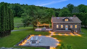Une maison en pierre avec un patio en pierre, un espace salon extérieur et un foyer.