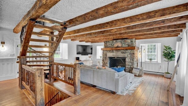 Un intérieur rustique avec des poutres apparentes, une cheminée en pierre et un coin salon confortable.
