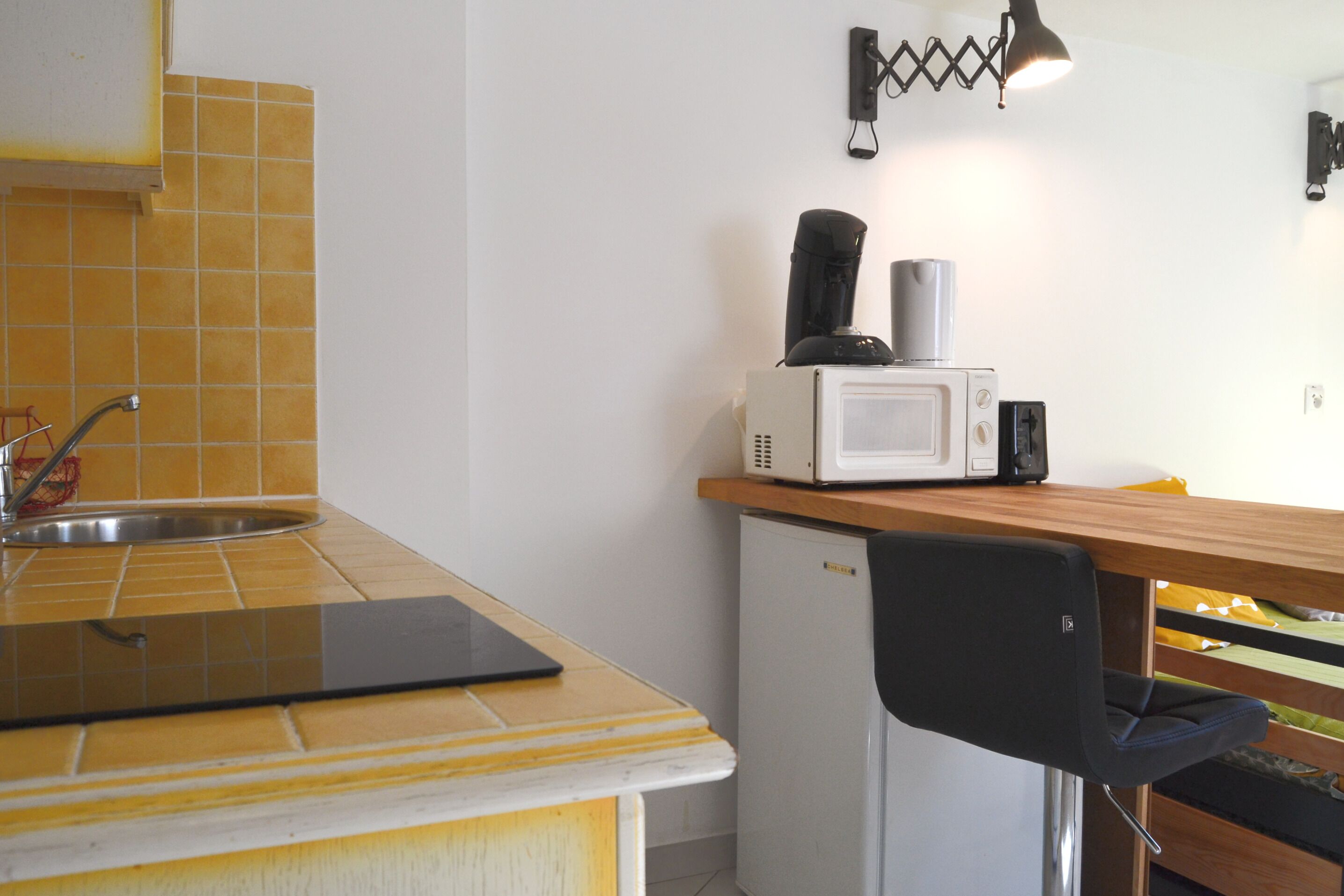 A compact kitchen with a sink, a microwave, and a small refrigerator.