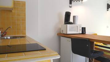 A compact kitchen with a sink, a microwave, and a small refrigerator.