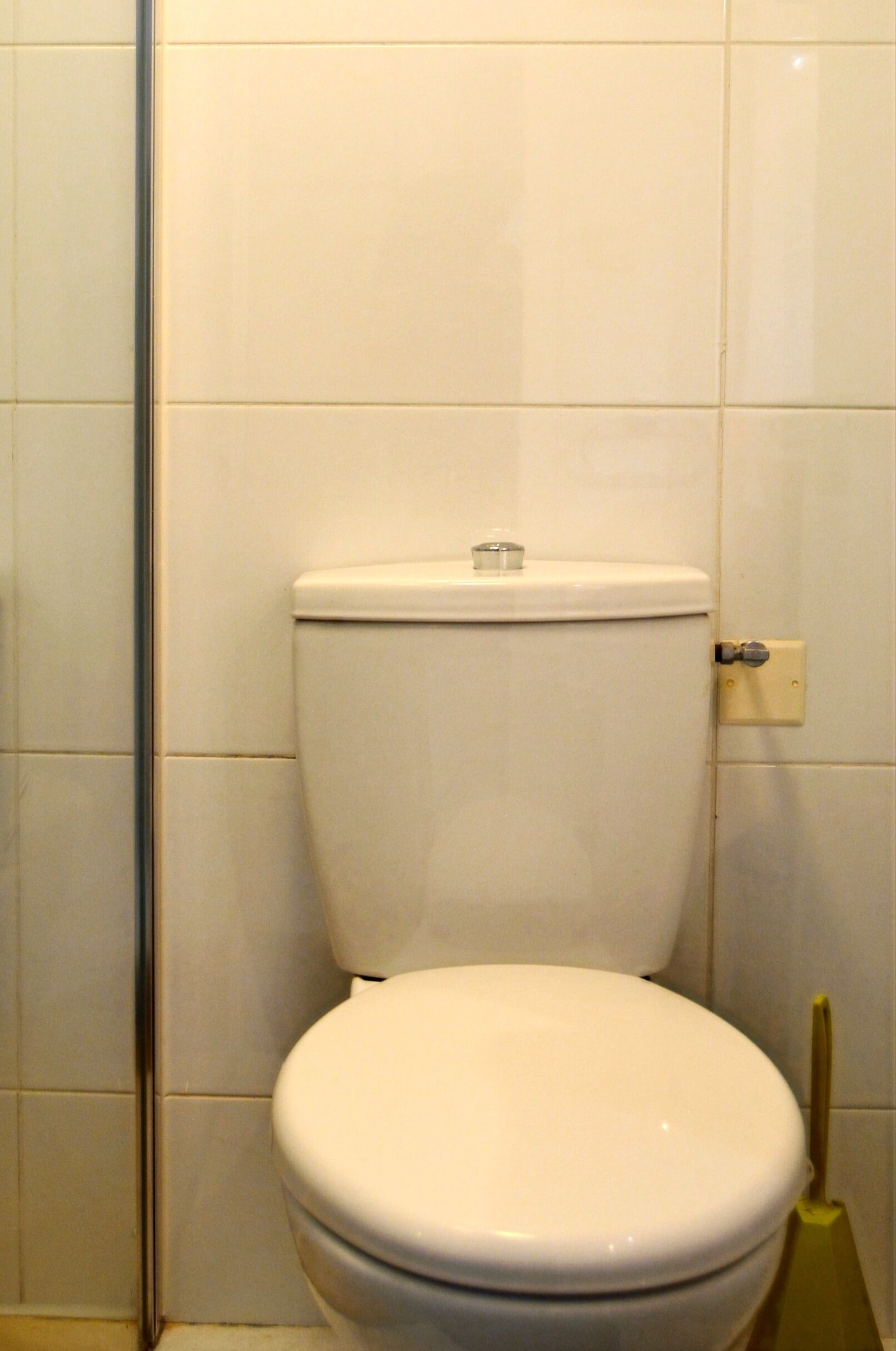 A white toilet in a bathroom with white tiles on the walls.