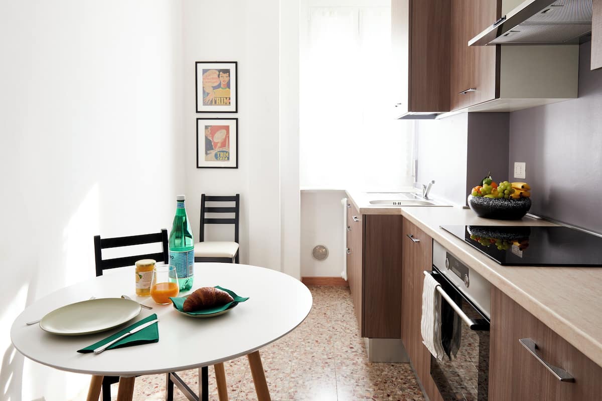 A modern kitchen with a round dining table, chairs, a sink, and a stove.
