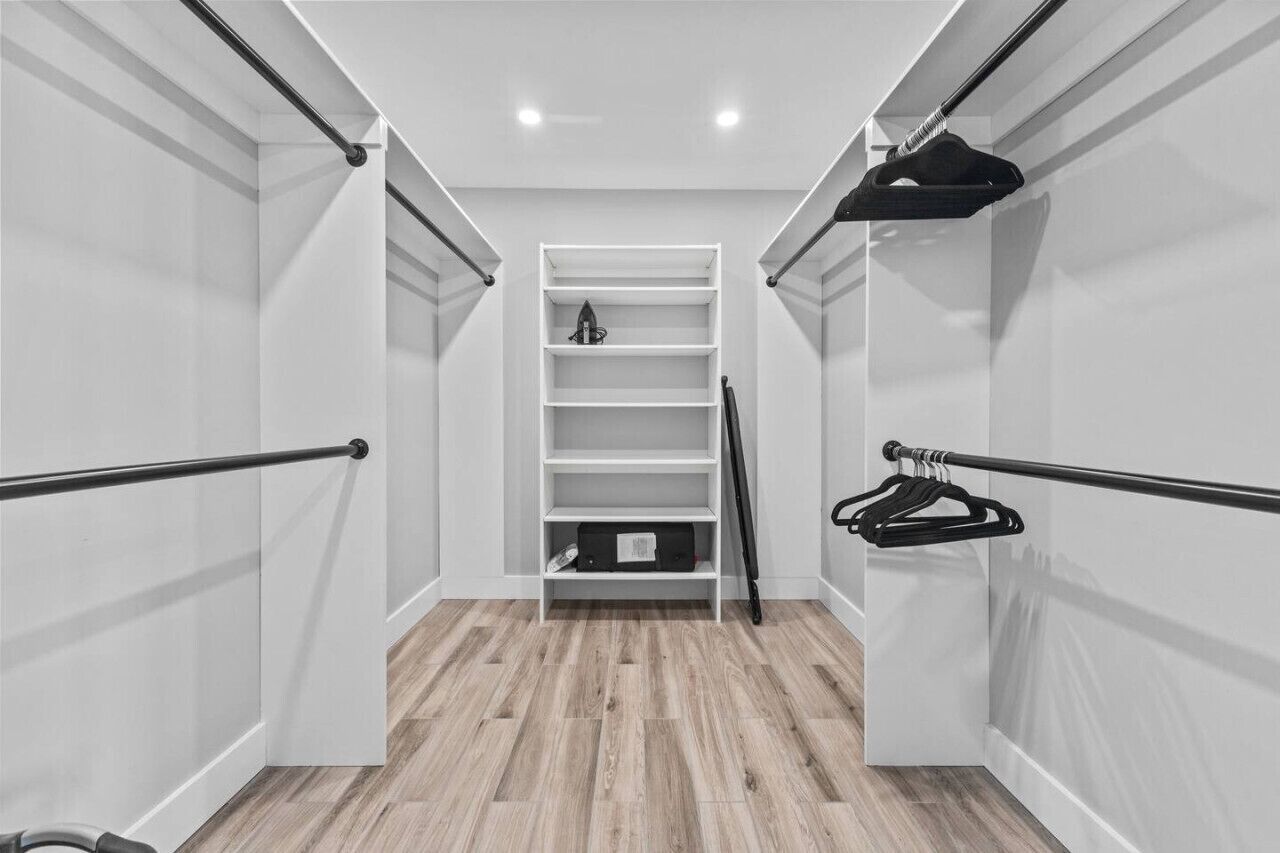 Un dressing avec des étagères blanches, une tringle à vêtements et un porte-chaussures.