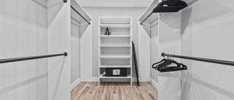 Un dressing avec des étagères blanches, une tringle à vêtements et un porte-chaussures.