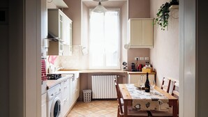 A compact kitchen with a washing machine, a dining table with chairs, a radiator, and cabinets. - Elle Home: comfort in Bologna (Bologna)