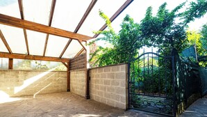 A covered outdoor area with a stone floor, a metal gate, and a view of greenery. - Elle Home: comfort in Bologna (Bologna)