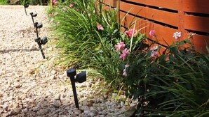 A wooden fence with a wooden deck attached to a building, surrounded by gravel and plants. - The River House - Island Getaway on the Steinhatchee River (Steinhatchee)