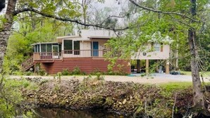 A cabin with a balcony, a covered porch, and a small pond in front. - The River House - Island Getaway on the Steinhatchee River (Steinhatchee)