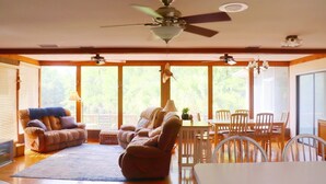 A spacious living area with a large window, a ceiling fan, a dining table, and a sofa. - The River House - Island Getaway on the Steinhatchee River (Steinhatchee)
