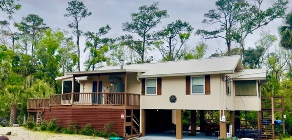 A two-story building with a balcony, a covered porch, and a garage. - The River House - Island Getaway on the Steinhatchee River (Steinhatchee)