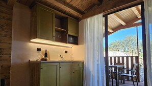 Een houten interieur met een keuken, een eethoek met buitenterras en uitzicht op de omgeving.