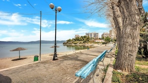 A waterfront promenade with benches, a trash bin, and a lamp post.