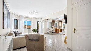 A spacious living area with a sofa, a dining table, and a kitchen in the background.