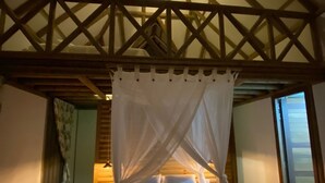 A bedroom with a wooden ceiling, a canopy bed, and a nightstand. - JENENÉ LODGE (Nuquí)