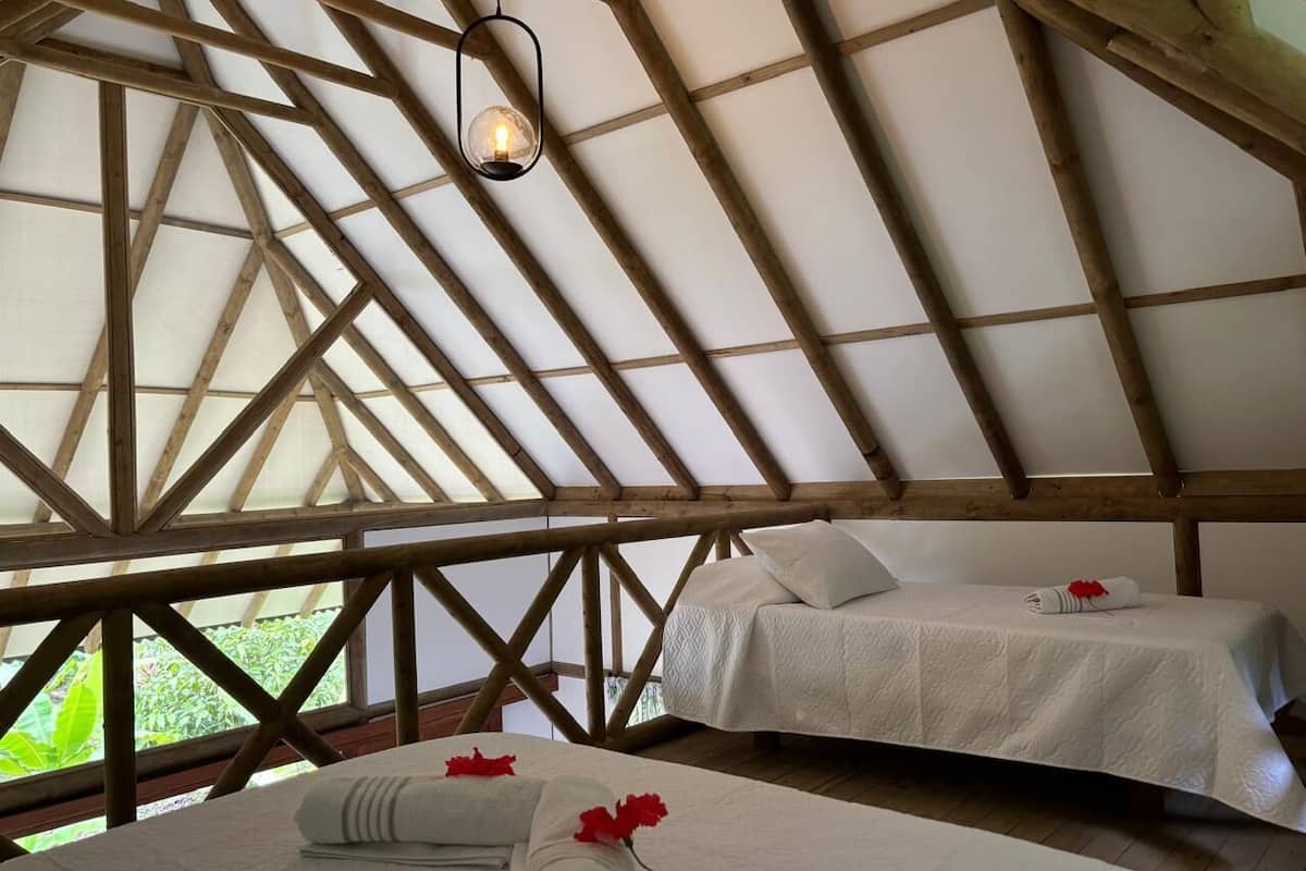 Quarto com teto de madeira alto e cama com colcha branca.