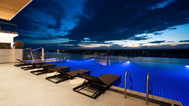 Une piscine à débordement offrant une vue sur les gratte-ciel de la ville au crépuscule.