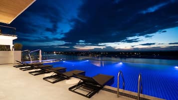 Una piscina al aire libre, sombrillas, sillones reclinables de piscina
